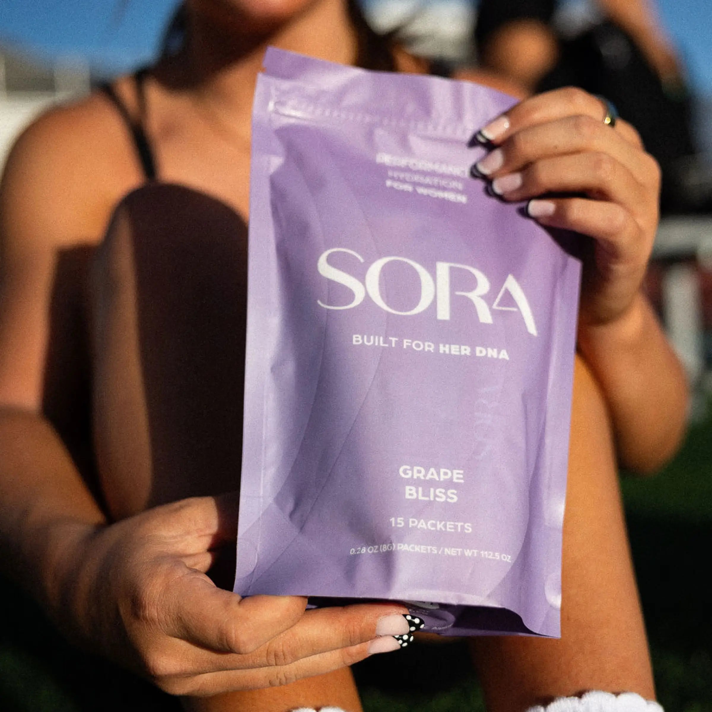 Woman holding a SORA Grape Bliss Performance Hydration pouch