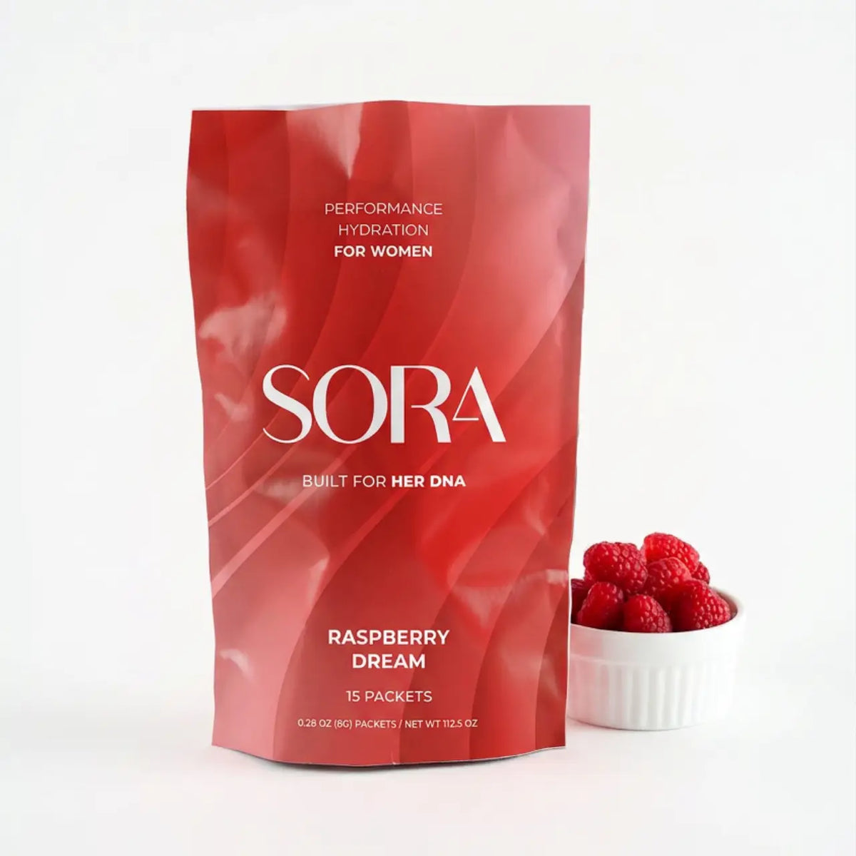 SORA Performance Hydration Raspberry Dream pouch next to a bowl of raspberries