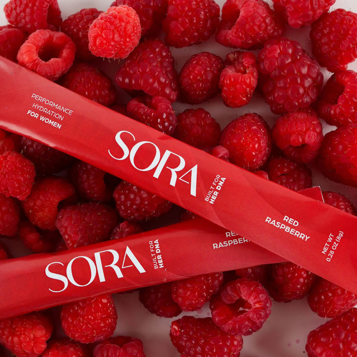 SORA Raspberry Dream stick packs on a bed of raspberries