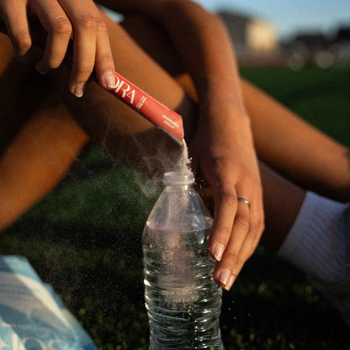 SORA Raspberry Dream stick pack being poured into a water bottle