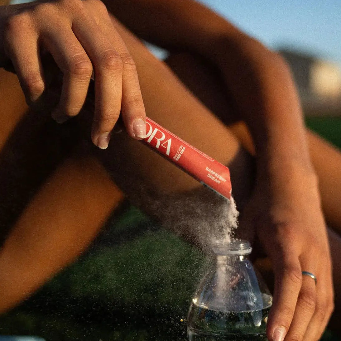 SORA Raspberry Dream stick pack being poured into a water bottle